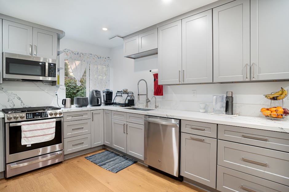 Sleek modern kitchen featuring stainless steel appliances and light grey cabinetry.