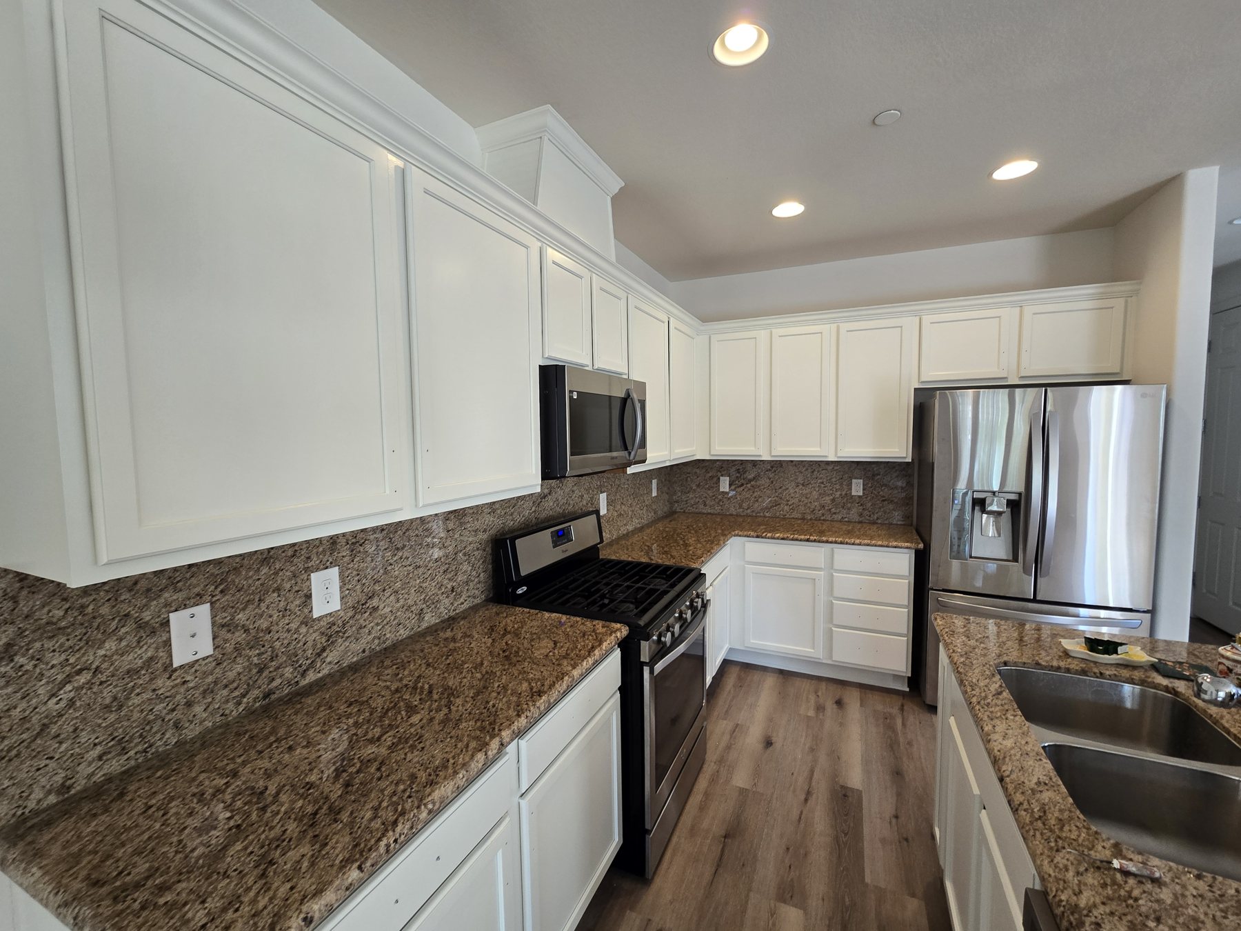 Kitchen cabinets sprayed white with granite counters by New Visions Painters in Las Vegas