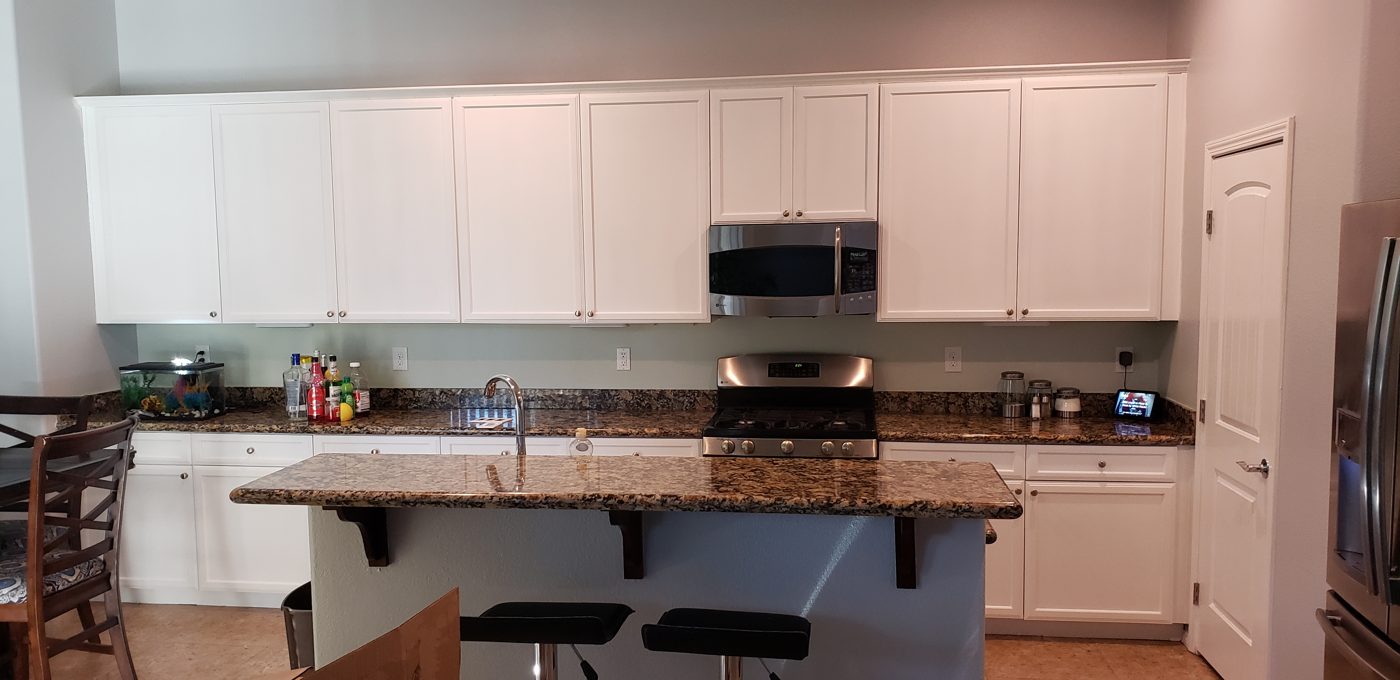 White kitchen cabinets professionally refinished with granite island in a Las Vegas home
